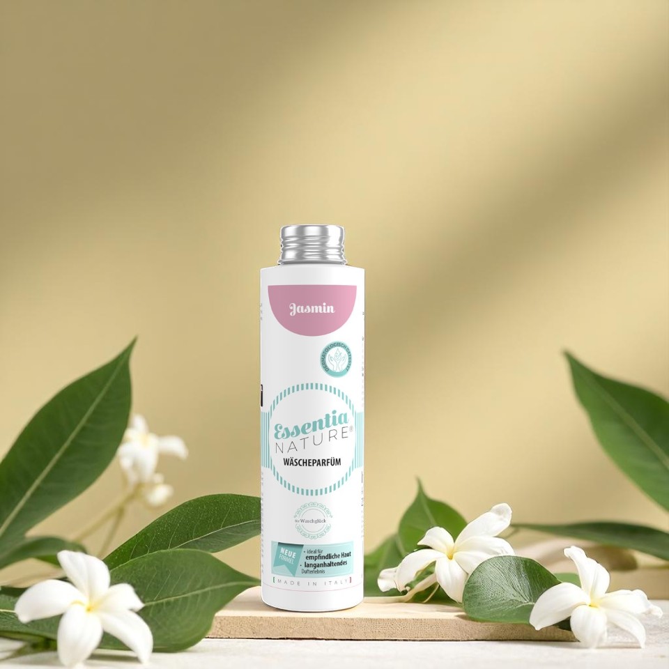 Essentia Nature Jasmin wasparfum in een witte fles met mintgroene en roze accenten, omringd door jasmijnbloemen en groene bladeren voor een natuurlijke, langdurige luxe geurbeleving bij Wasgeluk.