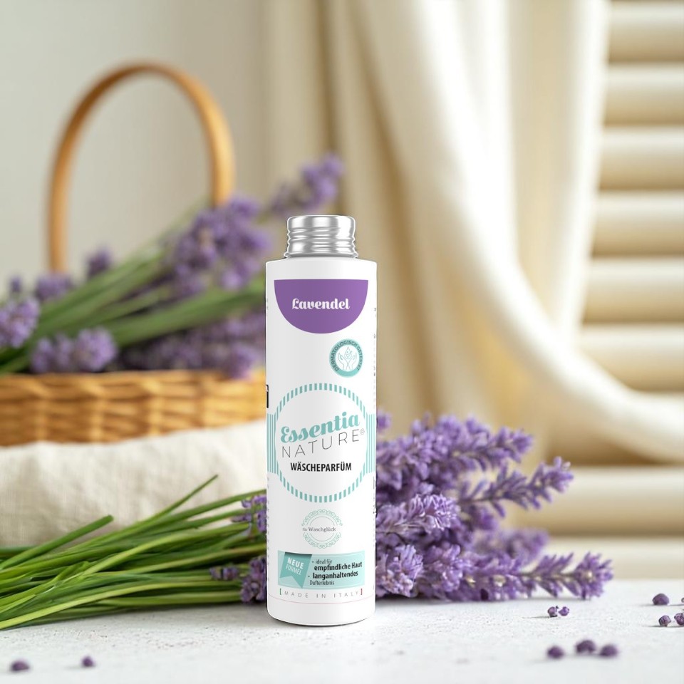 Essentia Nature wasparfum Lavendel van Wasgeluk in een witte en lila fles, sfeervol gefotografeerd tussen verse lavendel voor een langdurige, luxe en natuurlijke wasgeur.
