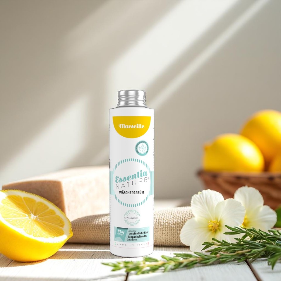 Wasgeluk Essentia Nature wasparfum Marseille in witte fles met geel label, omringd door citroen, zeep en bloemen voor een frisse, luxe en langdurige geurbeleving tijdens het wassen.