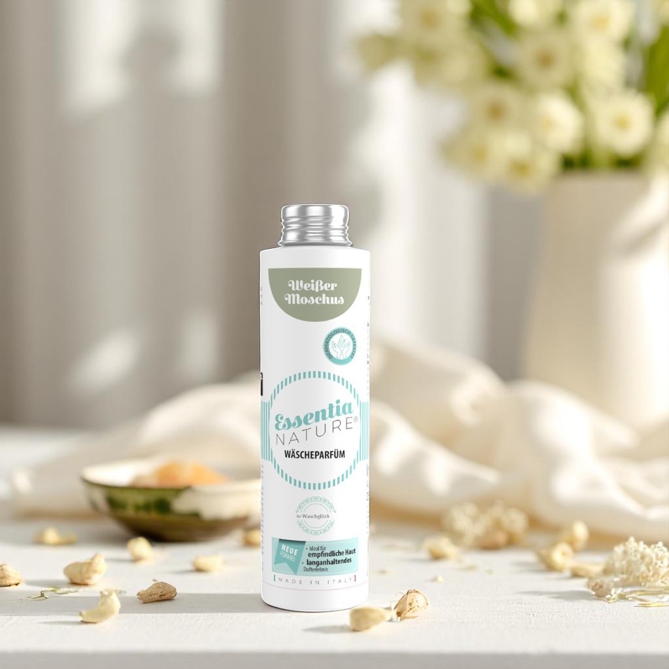 Essentia Nature wasparfum Weißer Moschus in een witte fles met mintgroene accenten, stijlvol gefotografeerd tussen lichte bloemen voor een natuurlijke, langdurige en luxe wasgeur zonder microplastics.