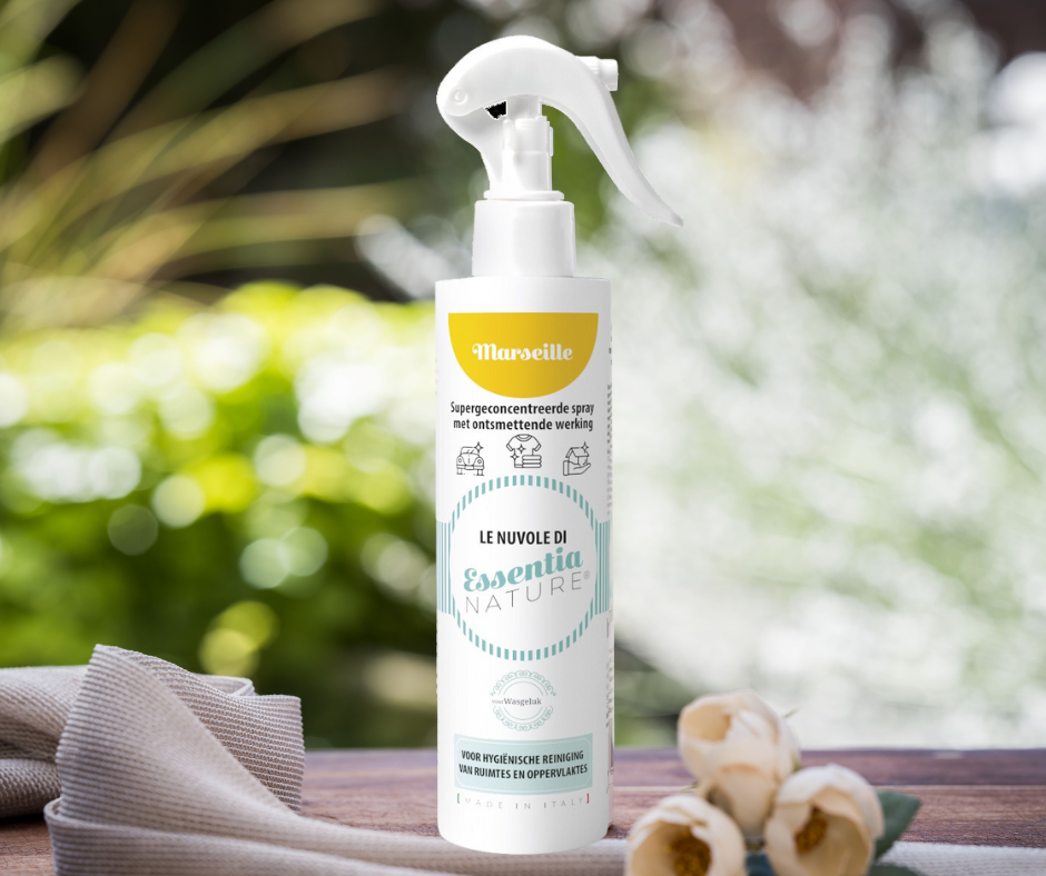 Wasgeluk Le Nuvole di Essentia Nature supergeconcentreerde Marseille sprayreiniger met ontsmettende werking in witte fles met geel label, gefotografeerd op een houten tafel met zachte bloemen op de voorgrond in een groene, natuurlijke tuinsetting.