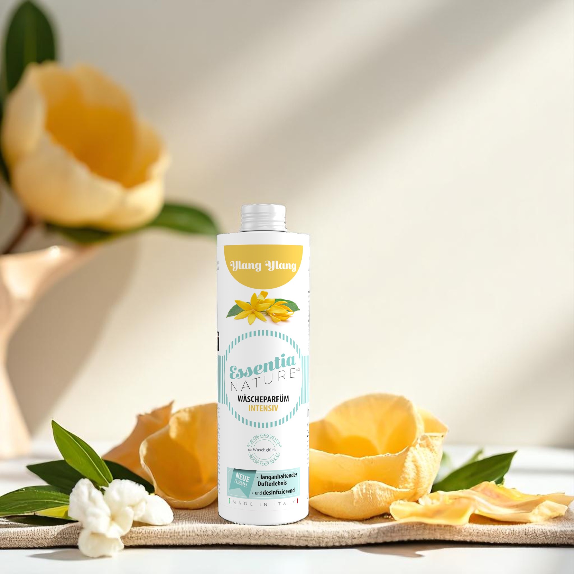 Essentia Nature wasparfum Ylang Ylang van Wasgeluk, duurzaam microplasticvrij wasparfum met langdurige luxe geurbeleving, sfeervol gefotografeerd tussen gele bloemblaadjes en groene bladeren.