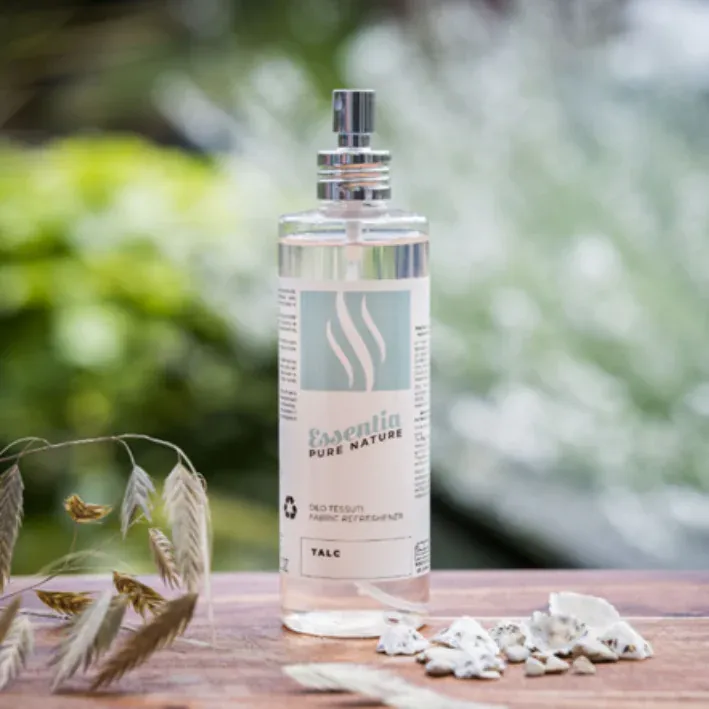 Essentia Pure Nature Talc was- en textielspray in transparante fles met zilverkleurige spraydop, gefotografeerd op een houten tafel met natuurlijke decoratie, voor een langdurige frisse en luxe geurbeleving.