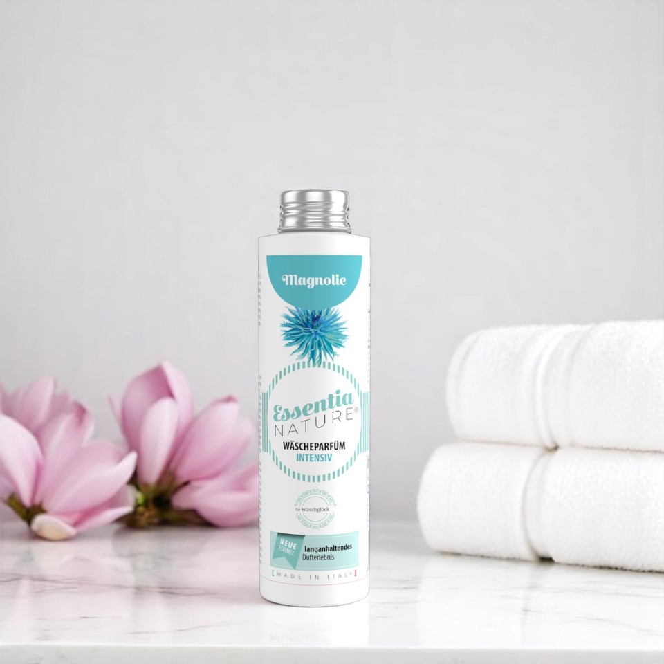 Essentia Nature wasparfum Intensiv Magnolie in witte fles met turquoise accenten, gestyled op marmeren badkamertafel met magnoliabloemen en opgerolde witte handdoeken voor een luxe, langdurige en microplasticvrije geurbeleving bij het wassen.
